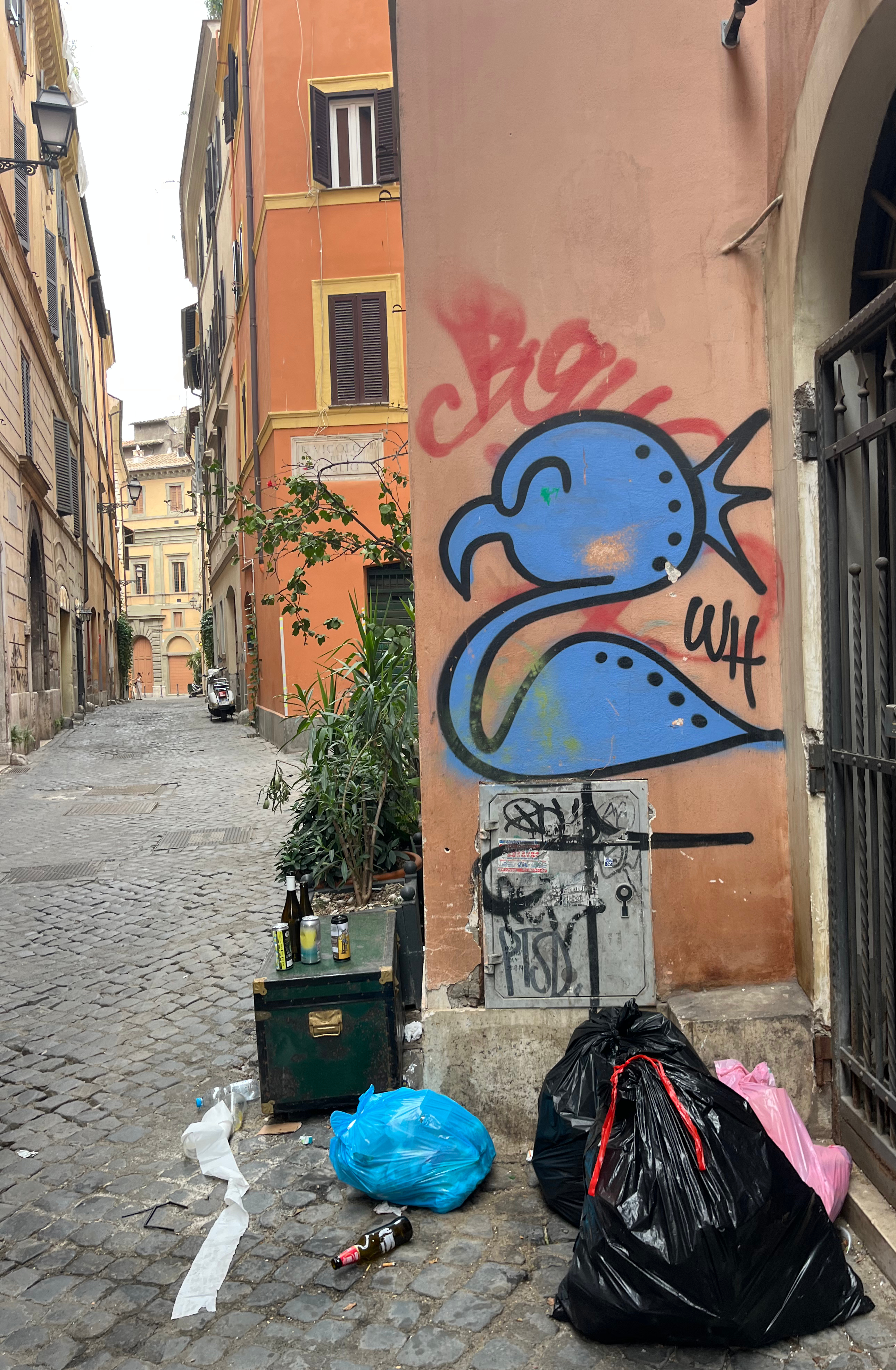 Trash bags collection point next to flamingo graffiti on Vicolo delle Grotte